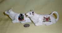 Two crested souvenir cow creamers, lying down