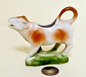 Small light brown and white cow creamer on green base