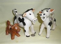 Small brown glazed Japanese curly-tailed cow creamer with two larger cousins