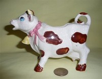 white cow creamer caricature with brown spots, blue eyes and pink bow