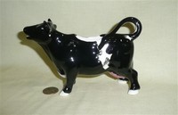 Mostly black cow creamer with white hooves and patch