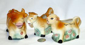 Three small Japanese brown cow creamers filled below with grass and pink flowers