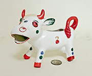 White cow caricature creamer with large head and red tail, horns and hooves