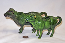 Two hand-molded green cow creamers