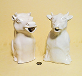 2 large sitting white cow pitchers