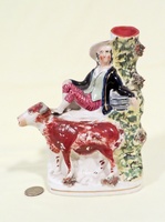Cow creamer spill vase with boy sitting next to  tree trunk