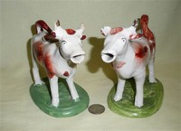 Pair of white and brown cow creamers on green bases