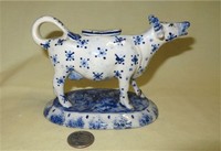 Cow creamer with blue decorations and long neck, with stapled repairs