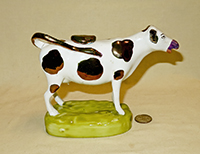 Bronze lustre nosed and spotted Swansea cow creamer on tall light green base