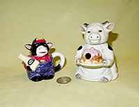 Miniature cow teapots, a farmer and a lady with a cake